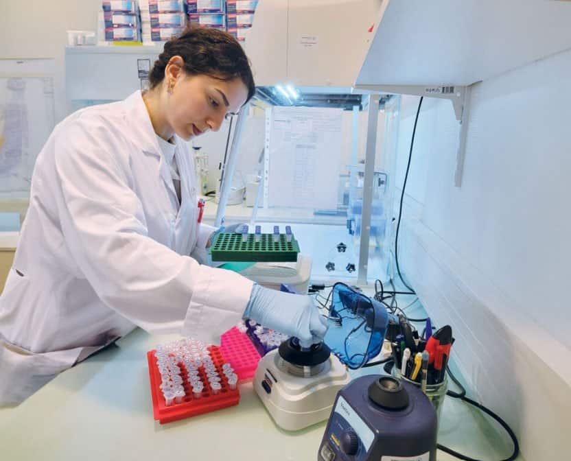 Researcher examining a specimen under a microscope in a regenerative medicine laboratory, representing decades of progress in stem cell science